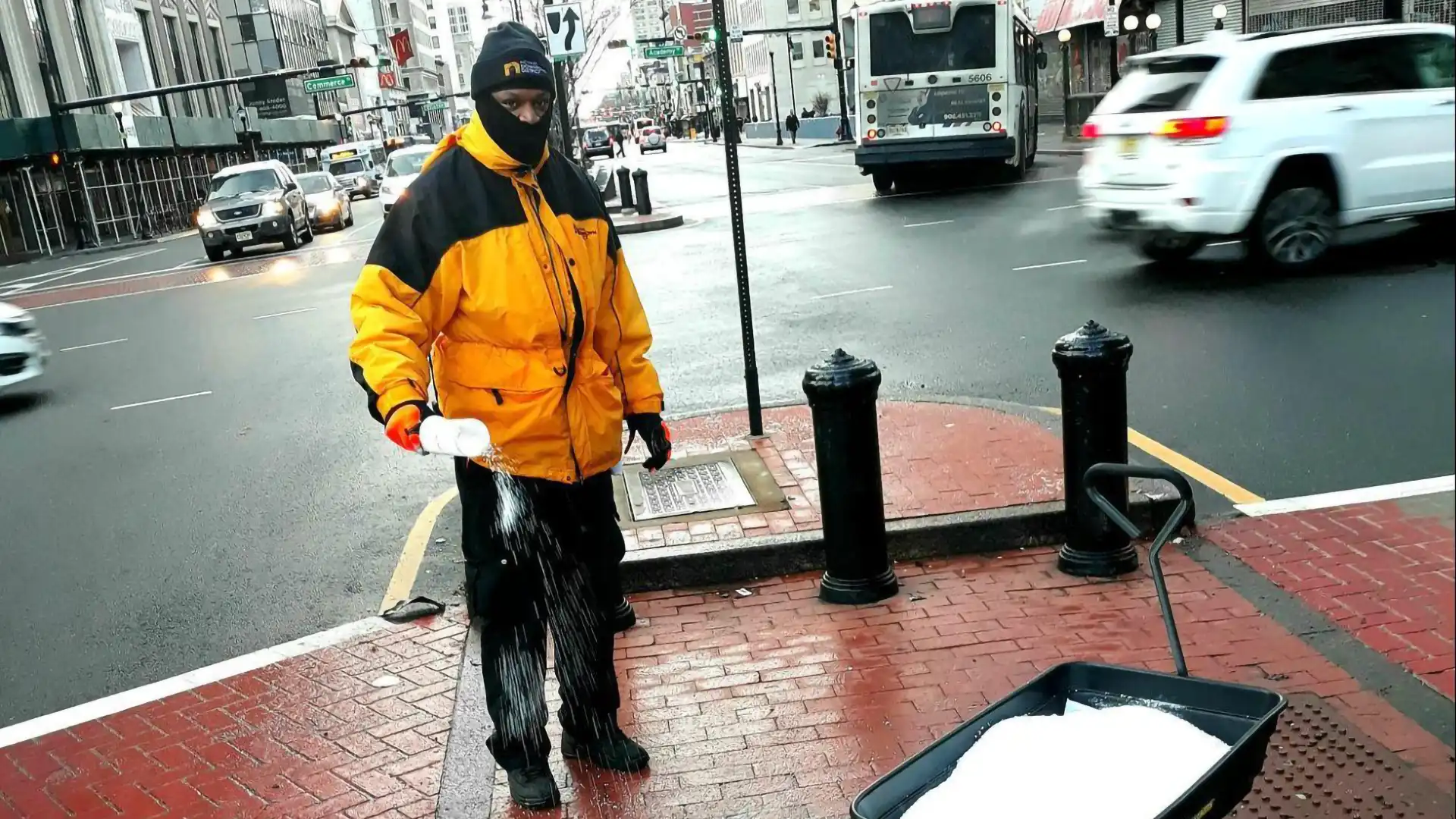 A maintenance worker spreading salt on the street.